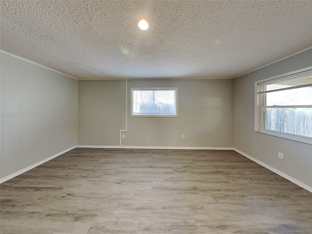 empty room with baseboards, a textured ceiling, wood finished floors, and crown molding