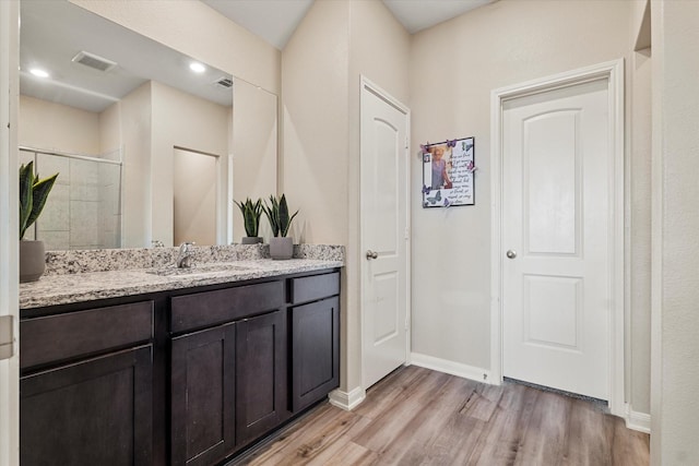 full bathroom featuring visible vents, wood finished floors, a shower stall, baseboards, and vanity