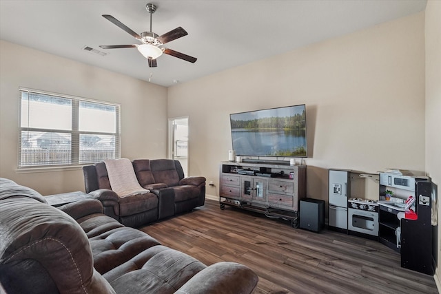 living area featuring visible vents, baseboards, dark wood-type flooring, and ceiling fan