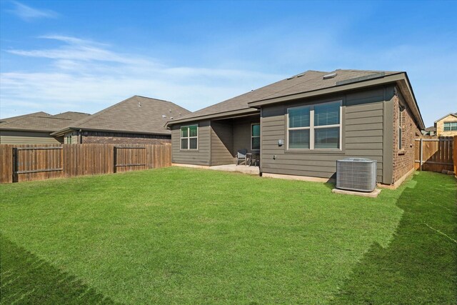 rear view of house with brick siding, cooling unit, a yard, a fenced backyard, and a patio area