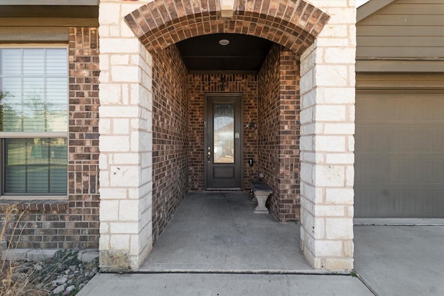 view of exterior entry with brick siding, stone siding, and an attached garage