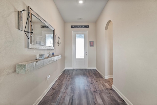 doorway featuring visible vents, arched walkways, dark wood-style flooring, and baseboards