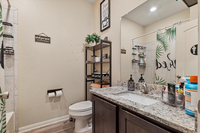 bathroom with baseboards, toilet, wood finished floors, and vanity