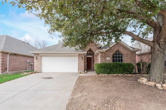 ranch-style house featuring brick siding, driveway, a shingled roof, and a garage