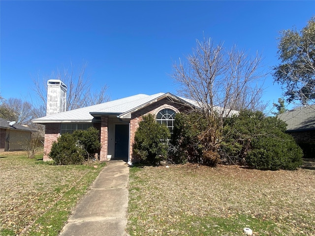 view of front facade featuring a front yard, brick siding, and a chimney