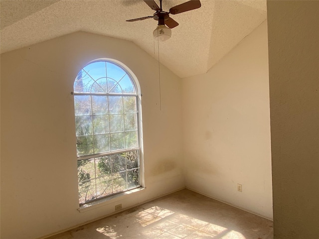 unfurnished room featuring plenty of natural light, a textured ceiling, ceiling fan, and vaulted ceiling