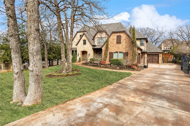 view of front of home featuring a front lawn, stone siding, fence, roof with shingles, and concrete driveway