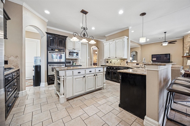 kitchen featuring a peninsula, arched walkways, stainless steel appliances, decorative backsplash, and open floor plan