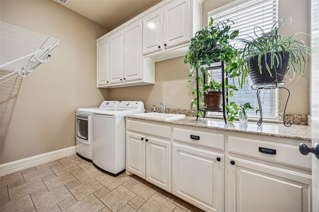 clothes washing area featuring cabinet space, independent washer and dryer, a wealth of natural light, and a sink