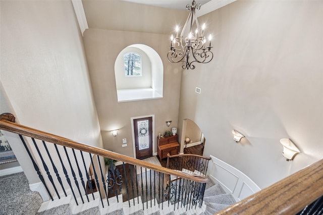 stairway with a high ceiling, a notable chandelier, carpet, and baseboards