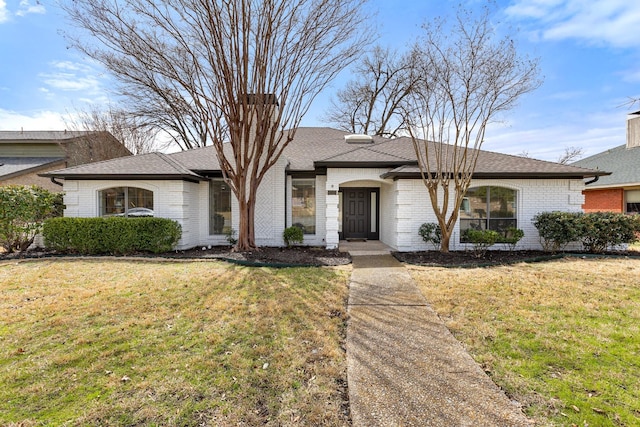 single story home featuring brick siding, a front lawn, and a shingled roof