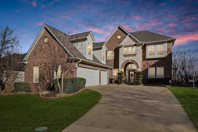 view of front of property featuring driveway, stone siding, a yard, an attached garage, and brick siding