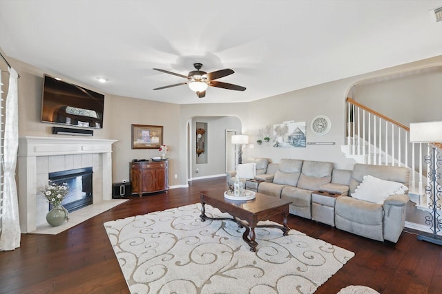 living area featuring hardwood / wood-style flooring, visible vents, arched walkways, and a tile fireplace