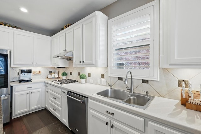 kitchen featuring under cabinet range hood, light countertops, stainless steel appliances, white cabinetry, and a sink