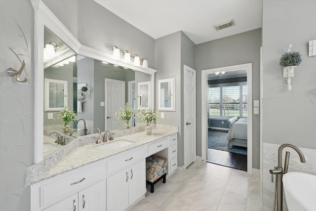 bathroom with visible vents, connected bathroom, a freestanding bath, marble finish floor, and vanity