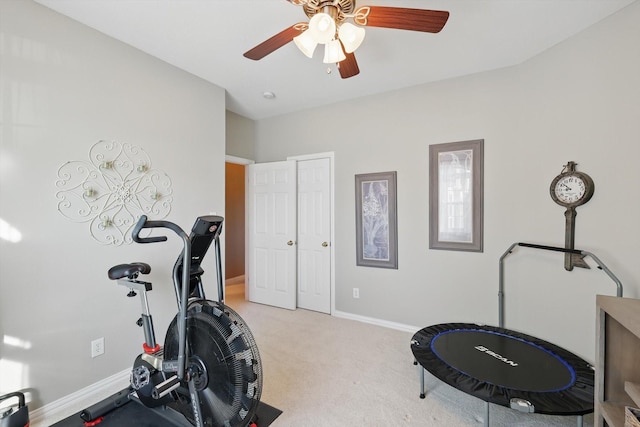 exercise area featuring baseboards, light carpet, and a ceiling fan