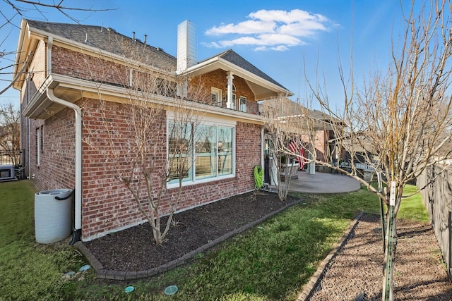 rear view of property with a patio, brick siding, a chimney, and a balcony