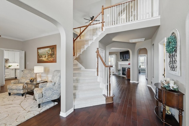 foyer entrance with baseboards, wood-type flooring, a glass covered fireplace, and ornamental molding