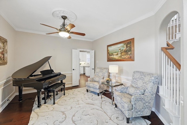 sitting room with arched walkways, ornamental molding, and wood finished floors