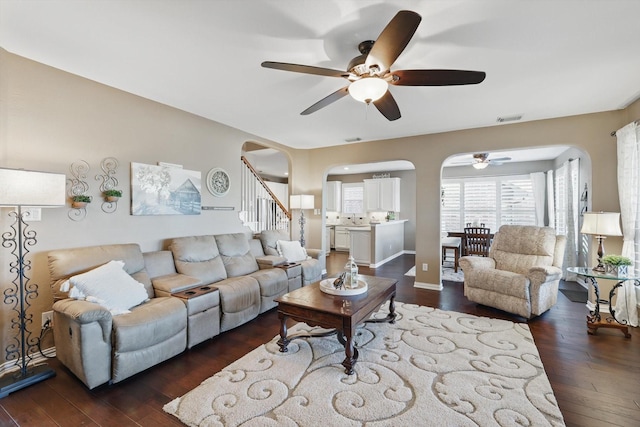 living room with arched walkways, visible vents, stairway, and dark wood-style flooring