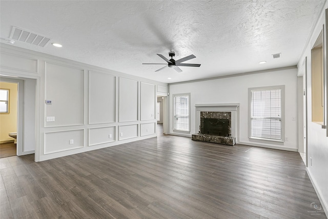 unfurnished living room with a decorative wall, plenty of natural light, visible vents, and a premium fireplace