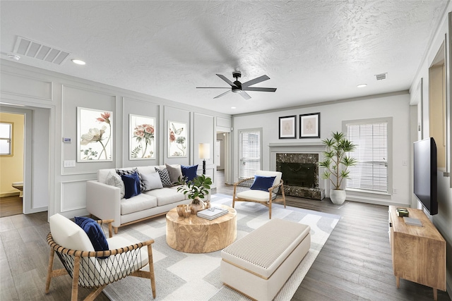 living area featuring a wealth of natural light, visible vents, a fireplace, and a decorative wall