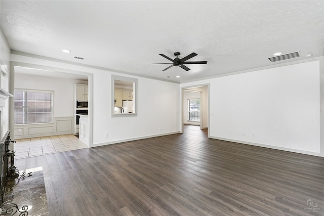 unfurnished living room featuring a fireplace with flush hearth, wood finished floors, visible vents, and ceiling fan