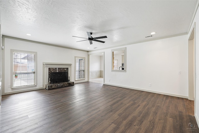 unfurnished living room with visible vents, a textured ceiling, dark wood finished floors, a fireplace, and ceiling fan