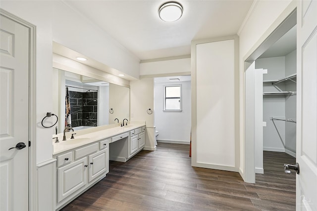 bathroom featuring a sink, toilet, wood finished floors, and double vanity