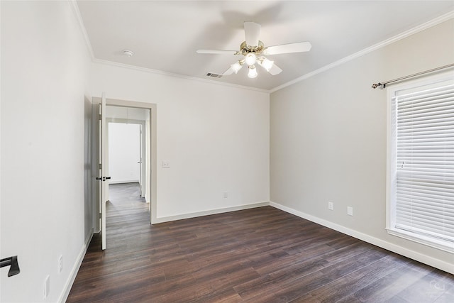 empty room featuring dark wood-style floors, visible vents, crown molding, and baseboards