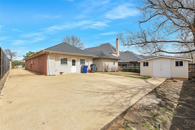 rear view of house featuring brick siding, an outdoor structure, a storage shed, and fence