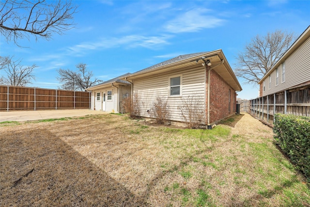 back of property featuring brick siding, a lawn, a patio, and a fenced backyard