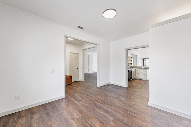 unfurnished room featuring dark wood finished floors, visible vents, baseboards, and ornamental molding