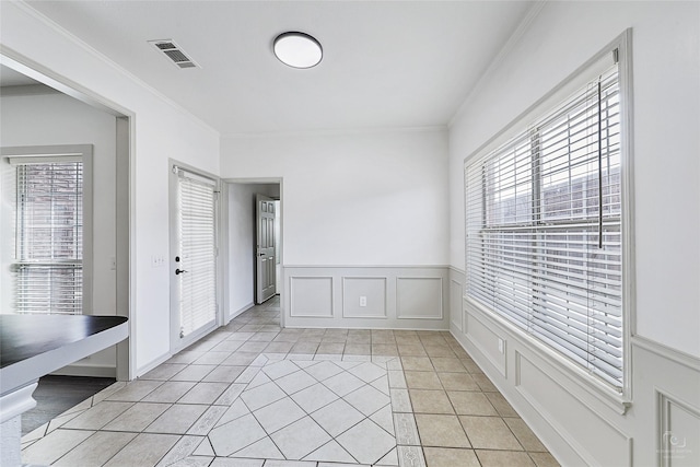 unfurnished room with a decorative wall, light tile patterned floors, visible vents, and ornamental molding