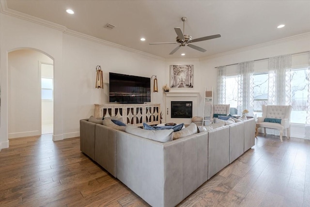 living area featuring recessed lighting, arched walkways, light wood finished floors, and ornamental molding