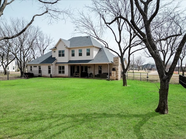 exterior space featuring a fenced backyard, board and batten siding, brick siding, and a yard