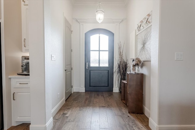 entrance foyer featuring baseboards, wood finished floors, and crown molding