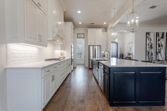 kitchen with visible vents, tasteful backsplash, white cabinetry, stainless steel appliances, and crown molding