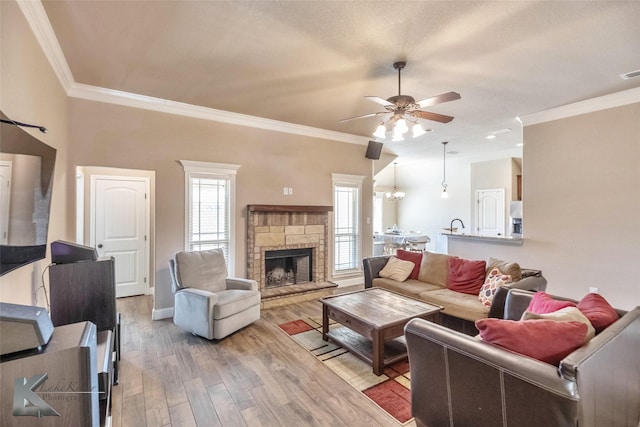 living room featuring a stone fireplace, crown molding, and light wood-type flooring