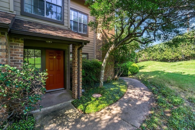 property entrance featuring brick siding, a lawn, and stone siding