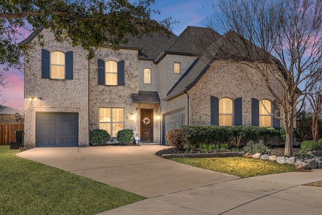 french provincial home with driveway, a front lawn, a garage, and roof with shingles