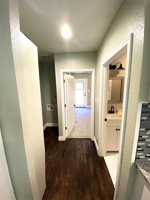 corridor featuring a sink, baseboards, and dark wood-style floors