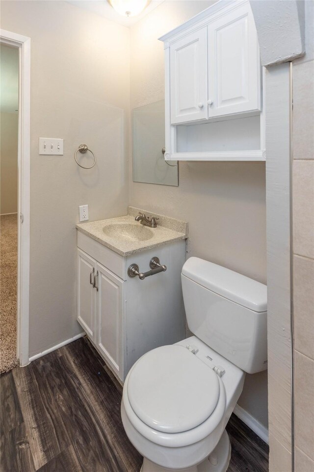 bathroom with baseboards, toilet, wood finished floors, and vanity