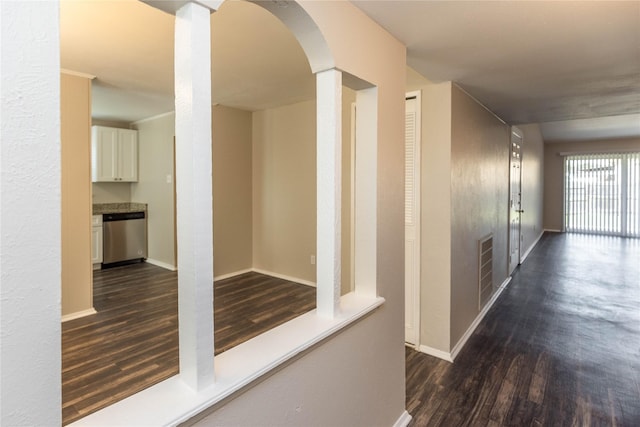 hallway with dark wood-style floors, visible vents, and baseboards