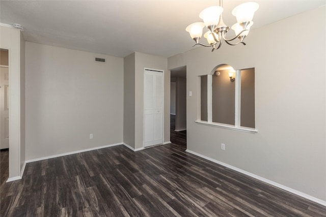 empty room featuring dark wood-style floors, visible vents, a notable chandelier, and baseboards