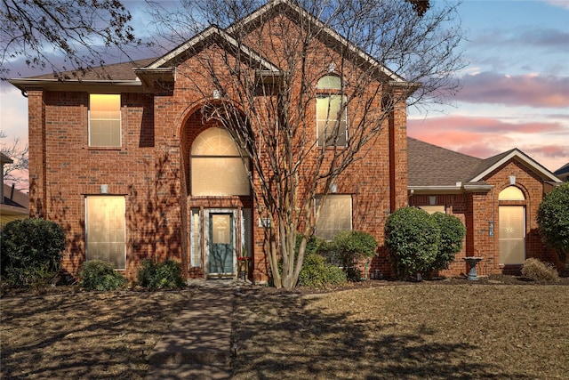 view of front of house featuring a front lawn, brick siding, and a shingled roof