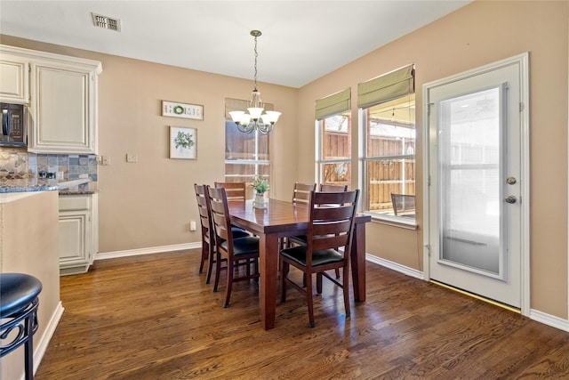 dining area featuring visible vents, baseboards, dark wood-type flooring, and a chandelier