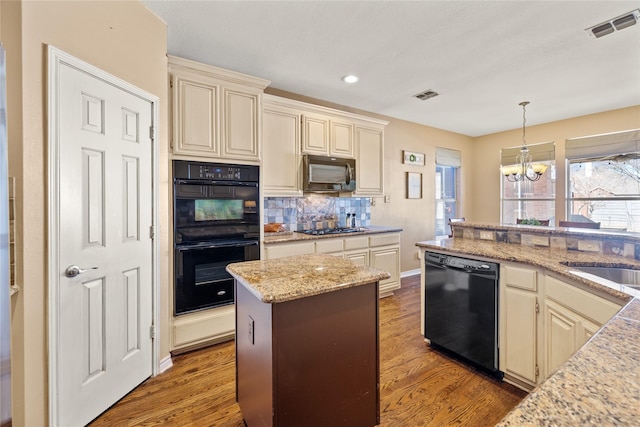 kitchen with visible vents, cream cabinets, black appliances, and wood finished floors