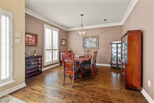 dining room with dark wood finished floors, crown molding, and baseboards