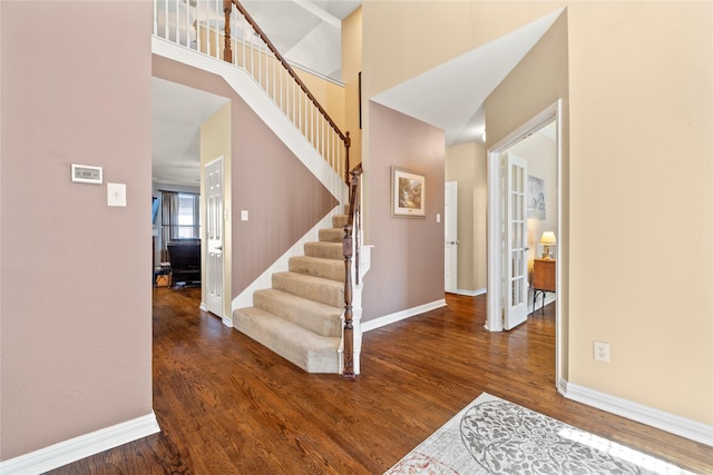 interior space with baseboards, a high ceiling, wood finished floors, and stairs